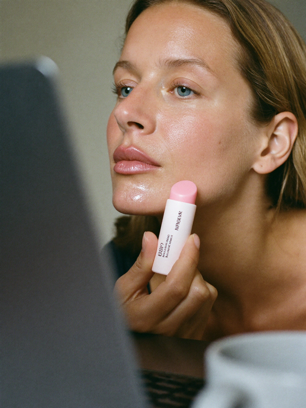 Woman touching up with a balm stick over makeup at her desk